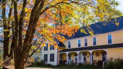 Large, iconic Vermont multi-level farmhouse surrounded by vibrant foliage in Mad River Valley Vermont