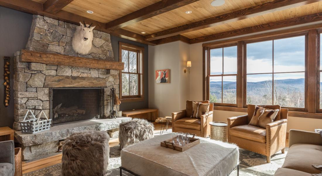 Luxurious and rustic living room with large wood beams and stone fireplace in the Mad River Valley Vermont.