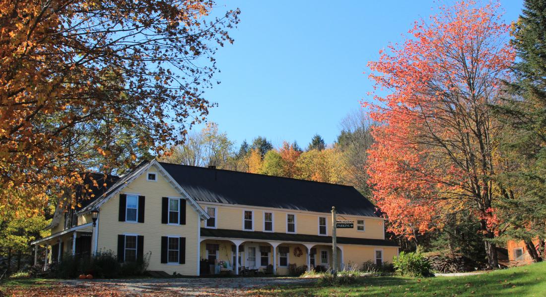 Beautiful, iconic multi-story Vermont farm house surrounded by vibrant fall colors.