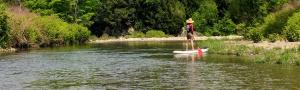 A person standup paddle-boarding on a tranquil river in the Mad River Valley Vermont