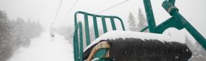 A snow dusted ski lift chair in front of snowy ski run in Mad River Valley Vermont